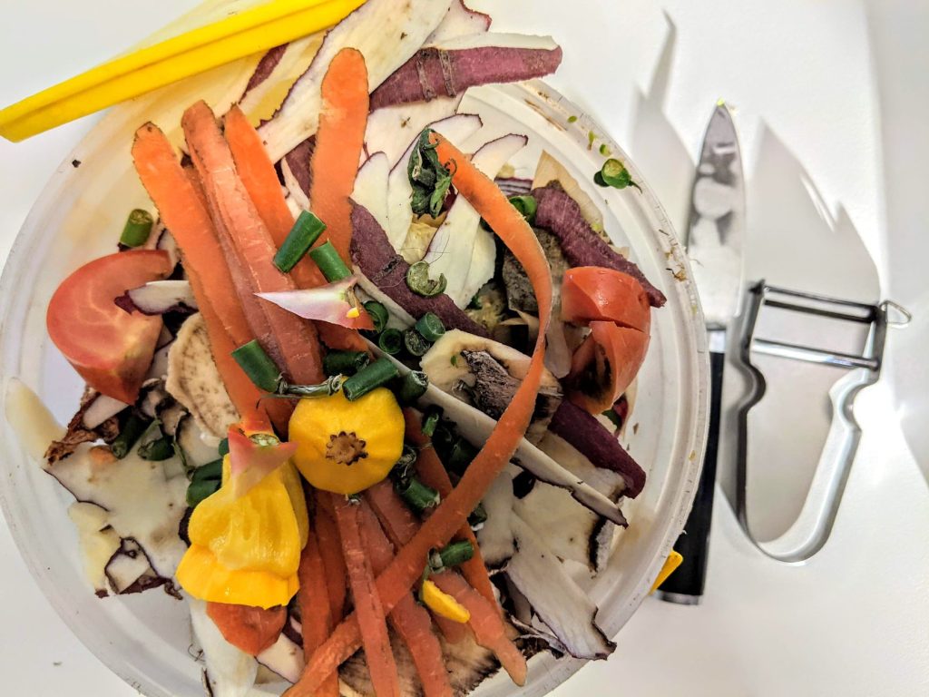 Bioseau de cuisine rempli d’épluchures de légumes prêtes à être compostées