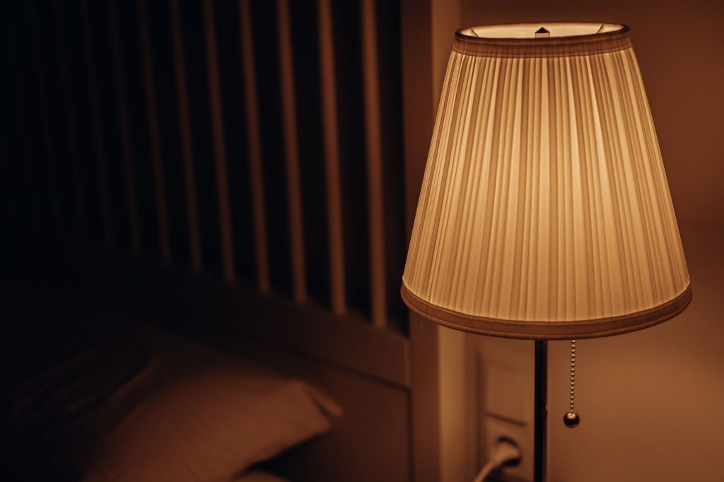 Lampe de chevet allumée diffusant une lumière orangée dans une chambre