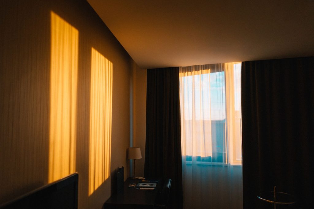Chambre lumineuse avec des rideaux encadrant la fenêtre au petit matin