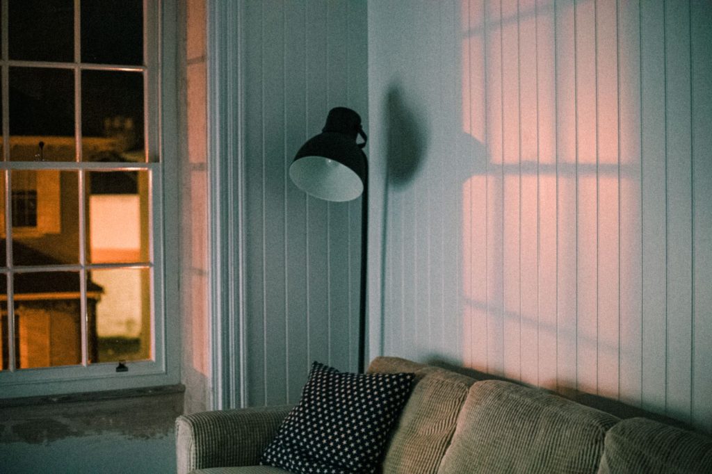 Salon avec canapé et lampadaire diffusant une lumière chaude