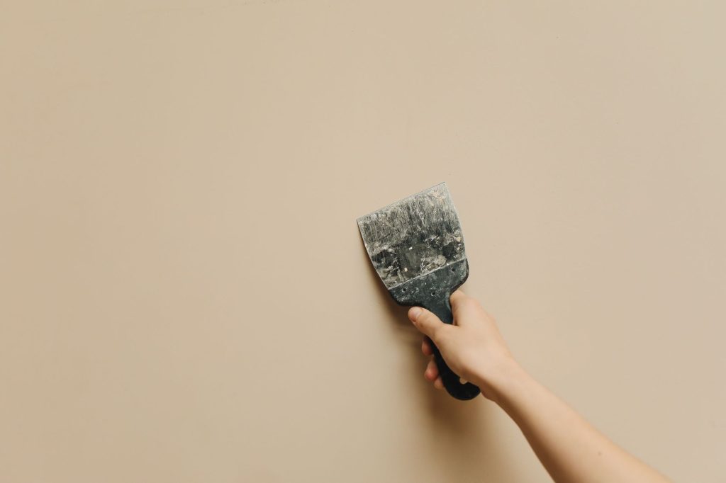 Application d'enduit de rebouchage sur un mur avec un couteau à enduire