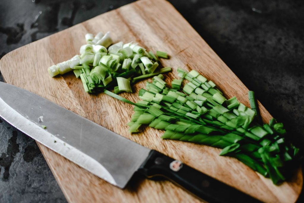Planche à découper en bois avec des légumes coupés et un couteau de cuisine