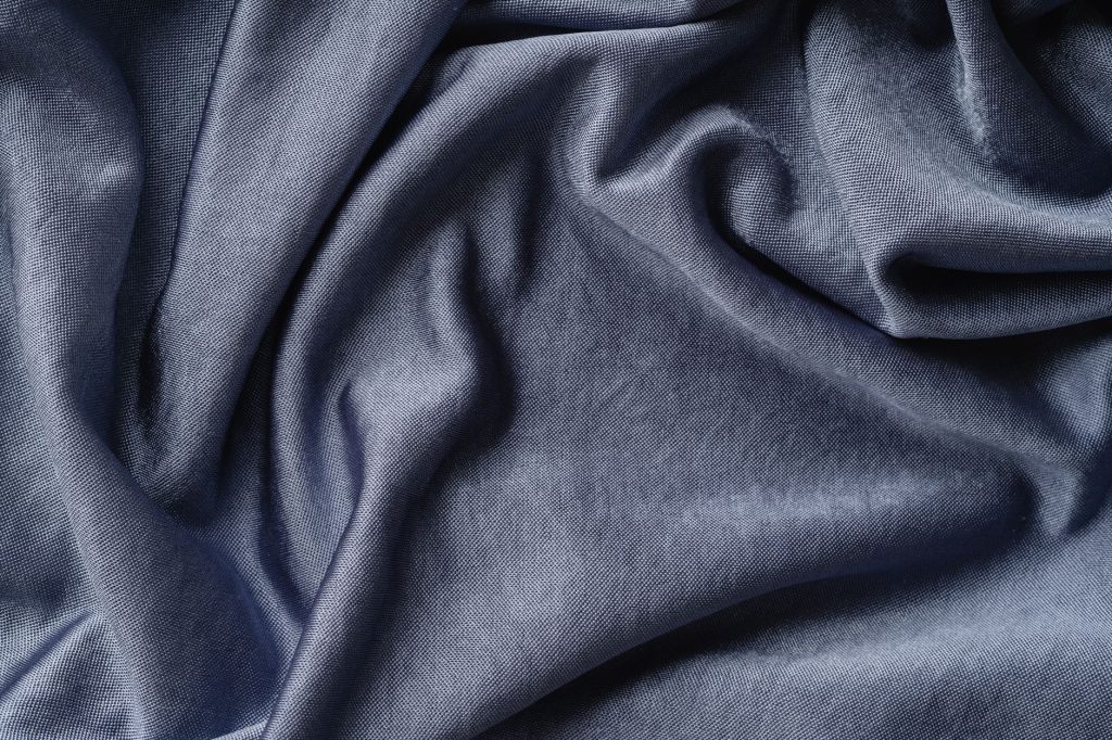 Gros plan sur la texture et les plis d'un rideau en tissu naturel clair