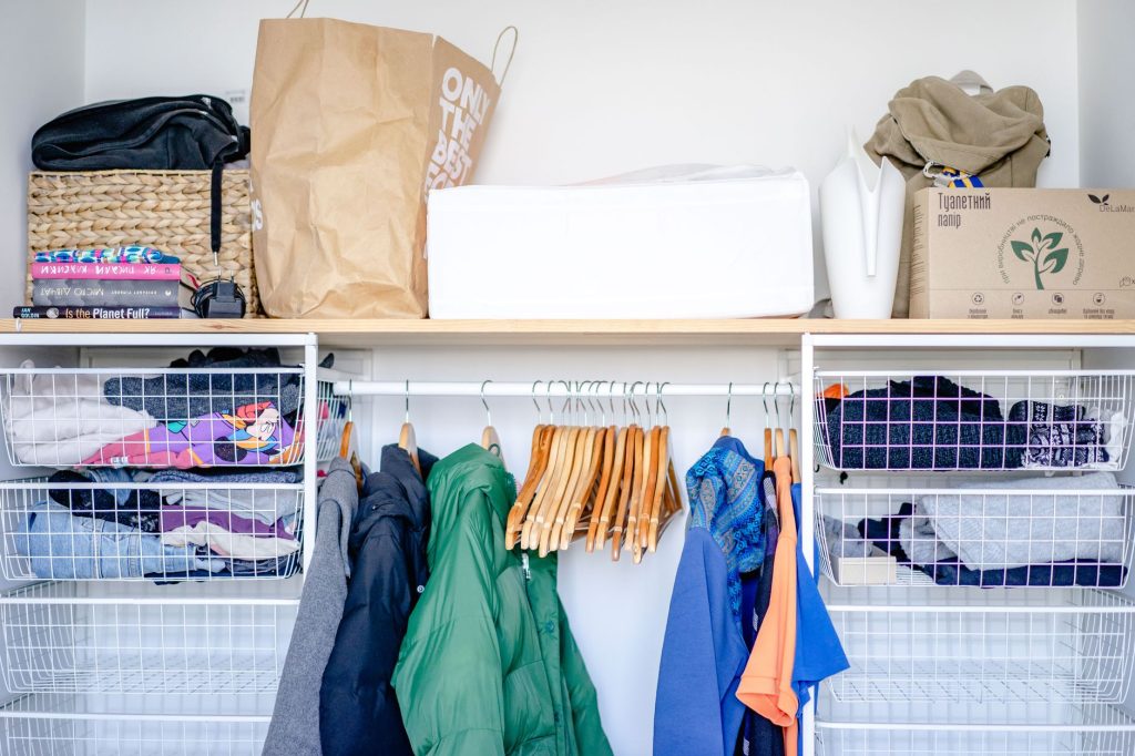 Rangement de vêtements pliés et paniers en osier dans un dressing organisé