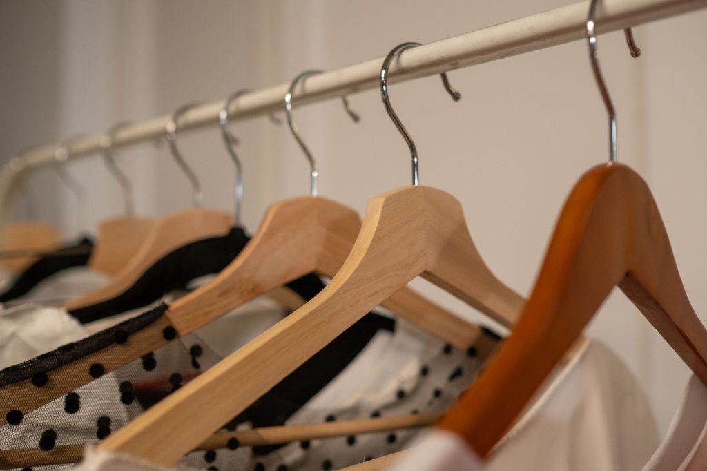 Penderie ouverte avec vêtements suspendus et étagères dans une petite chambre